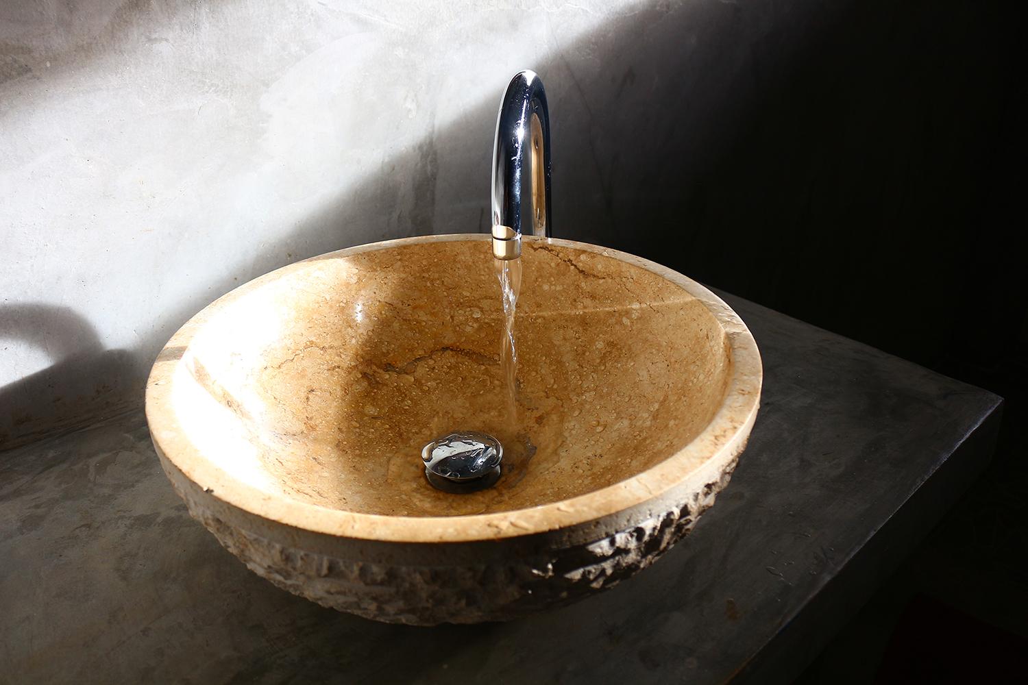 Round stone-like basin in the modern bathroom with running water