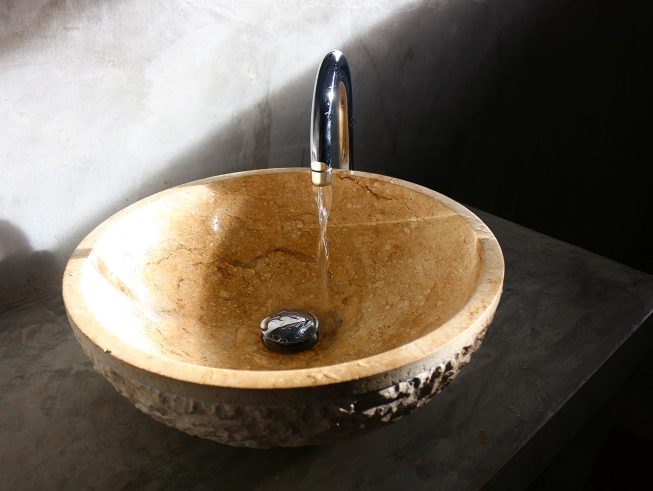 Round stone-like basin in the modern bathroom with running water